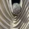 Large silver 3D wall sculpture titled Silver Veils by Samaa, featuring deep metallic fabric-like folds gathered around a central textured sphere on a dark background.