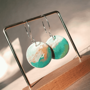 Round earrings hanging from a silver hook. Colours are green and brown.