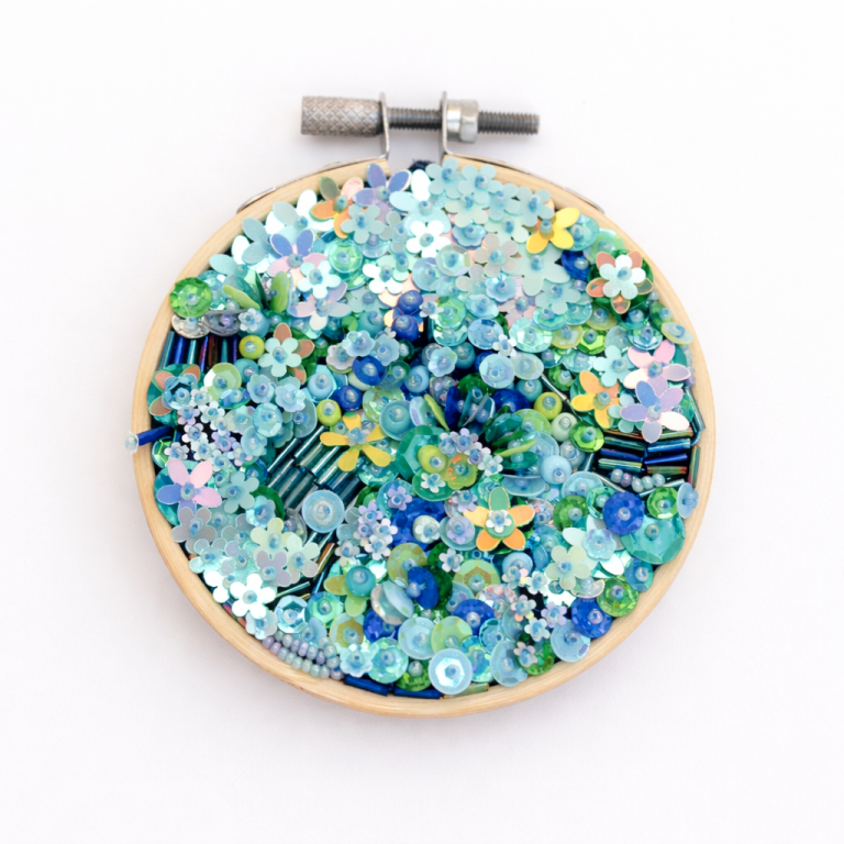 Background Noise, mixed media textile artwork by Samira Stephens with layered beads and sequins in a wooden embroidery hoop.